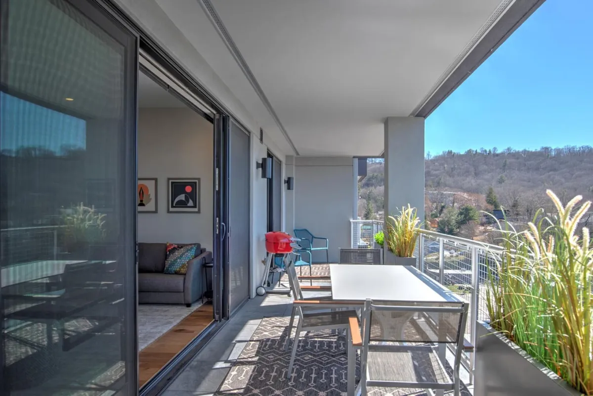 This image showcases a well-appointed outdoor dining space with a table set for meals, a grill perfect for barbecues, comfortable seating, and lush decorative plants. The setting evokes a casual atmosphere for relaxing with friends and enjoying views that connect the home to the energy of its surroundings.