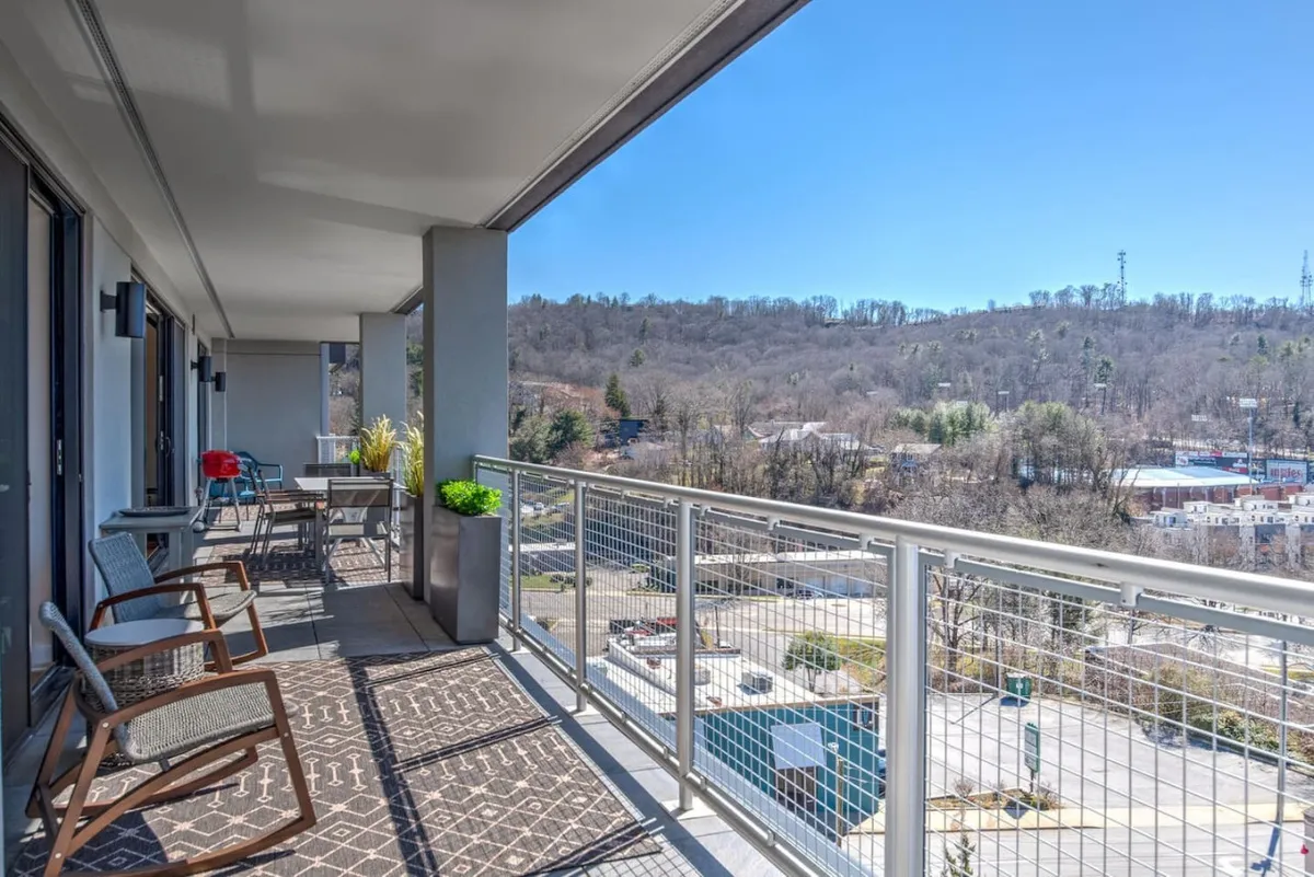 This image captures a private balcony outfitted with comfortable seating and decorative plants, all set against a sweeping landscape view. The tranquil mood and inviting setup highlight the balcony as a welcoming extension of the living space, perfect for relaxing or socializing while enjoying scenic vistas.